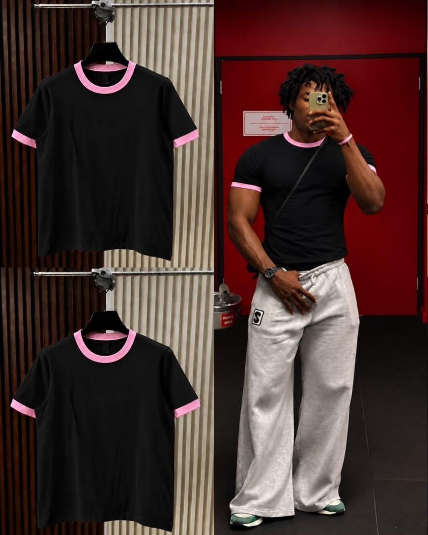 Black t-shirt with pink contrast trim on neck and cuffs, shown on hanger and model.