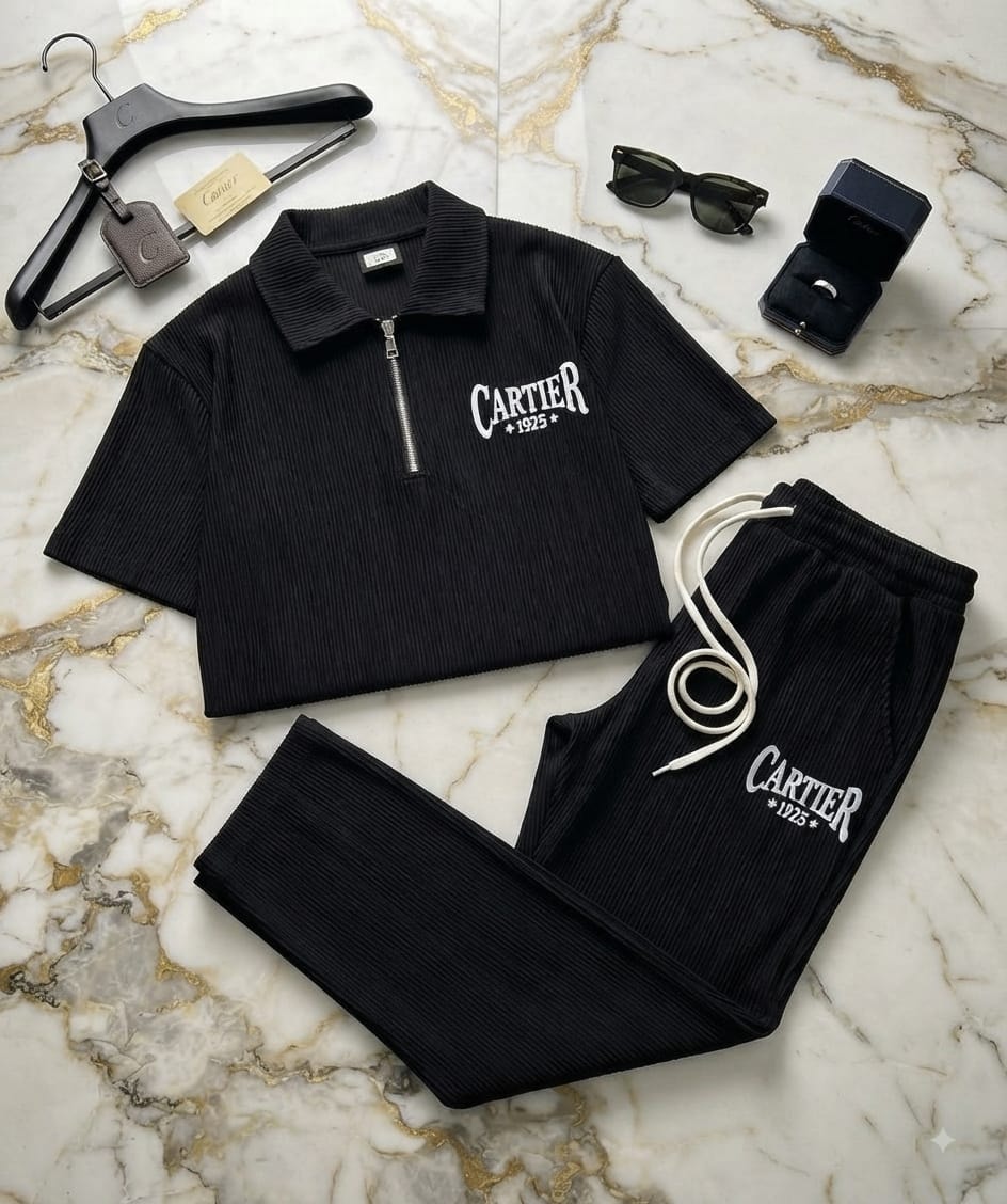 Black ribbed Cartier two-piece set with quarter-zip polo and matching joggers on marble surface with accessories.