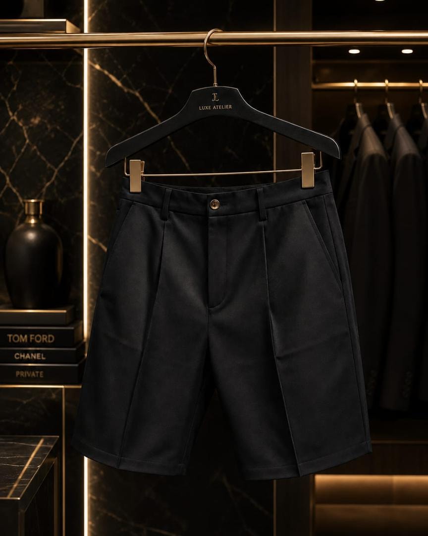 Black tailored pleated shorts hanging on gold hanger.