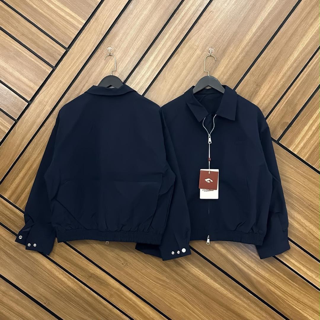 Navy unisex zip-up bomber jacket displayed from front and back with attached tag.