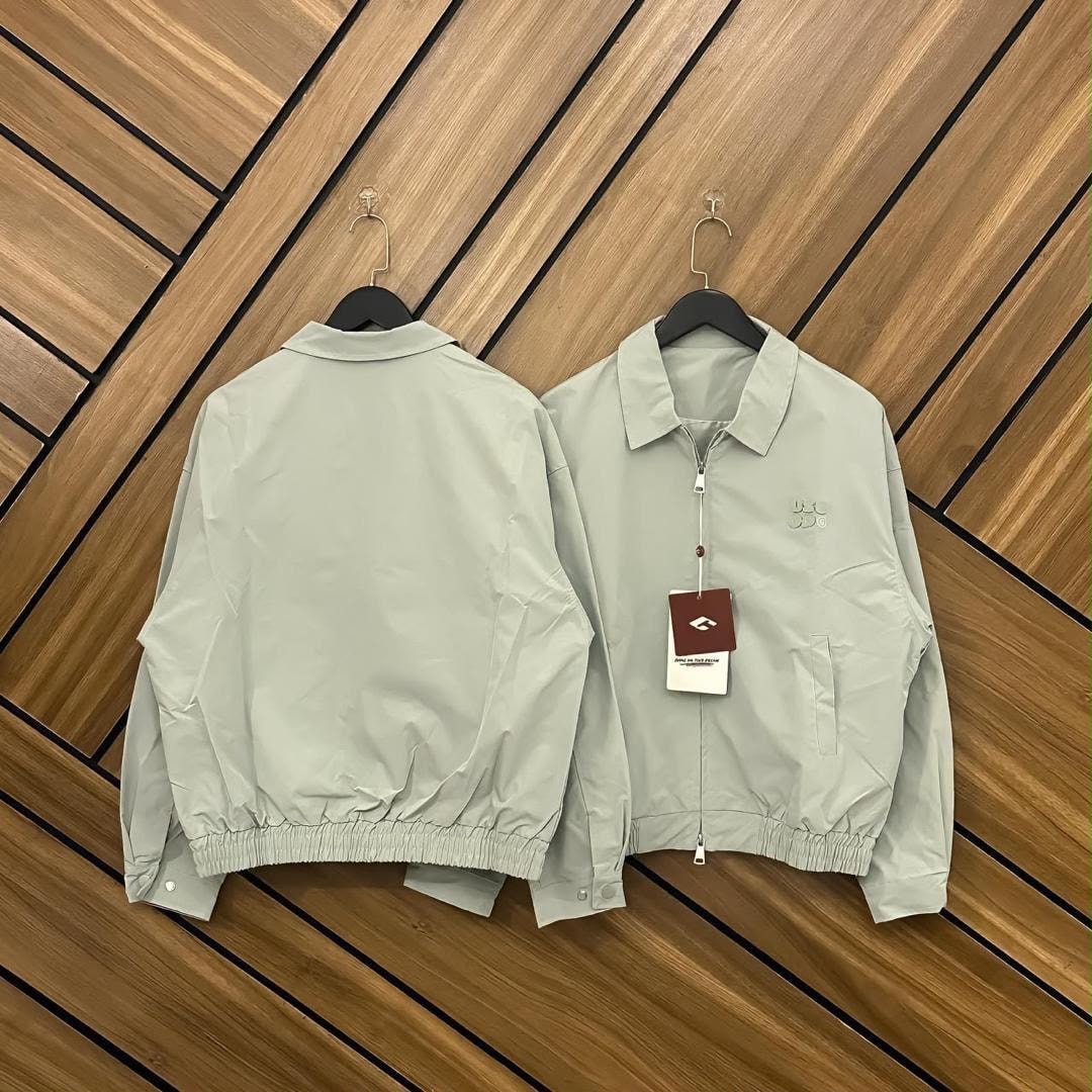 Light green unisex zip-up bomber jacket shown from front and back with attached tag.