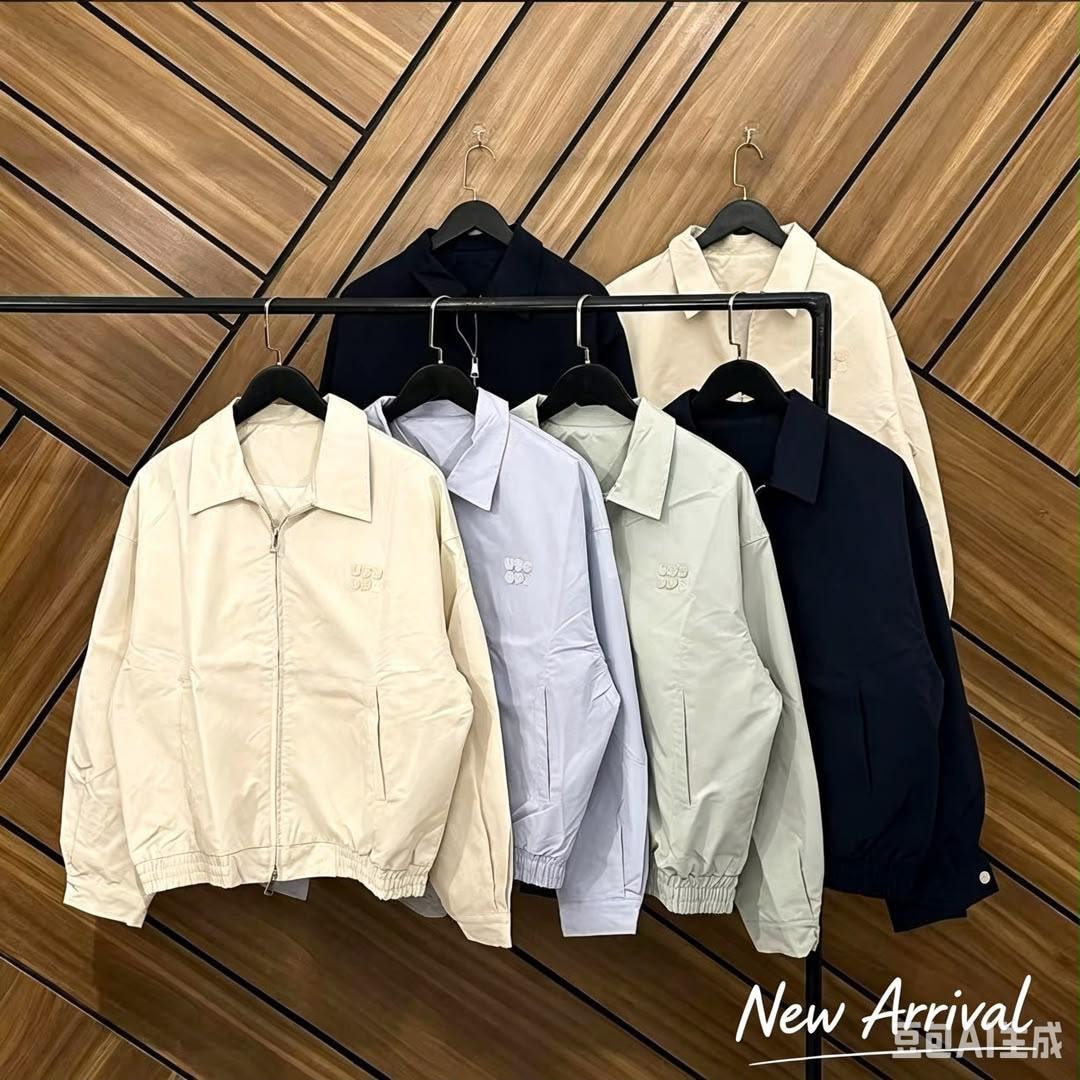 Group of unisex zip-up bomber jackets in cream, light blue, green and navy hanging together on a rack.