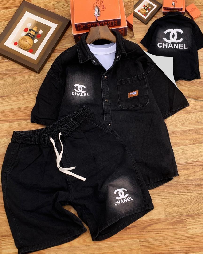 Flat lay of black denim shirt and shorts with white Chanel logos and accessories.