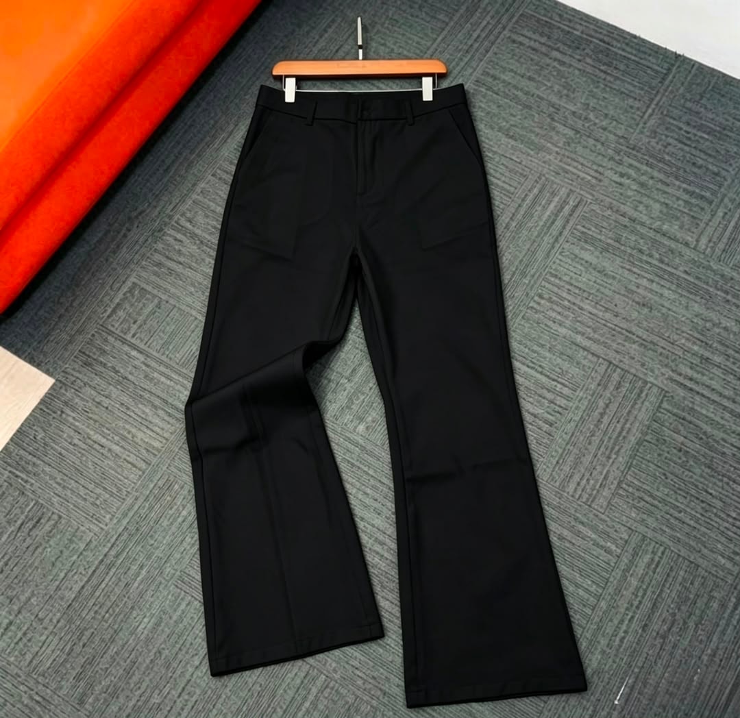 Black flare trousers shown flat on patterned rug with tag.