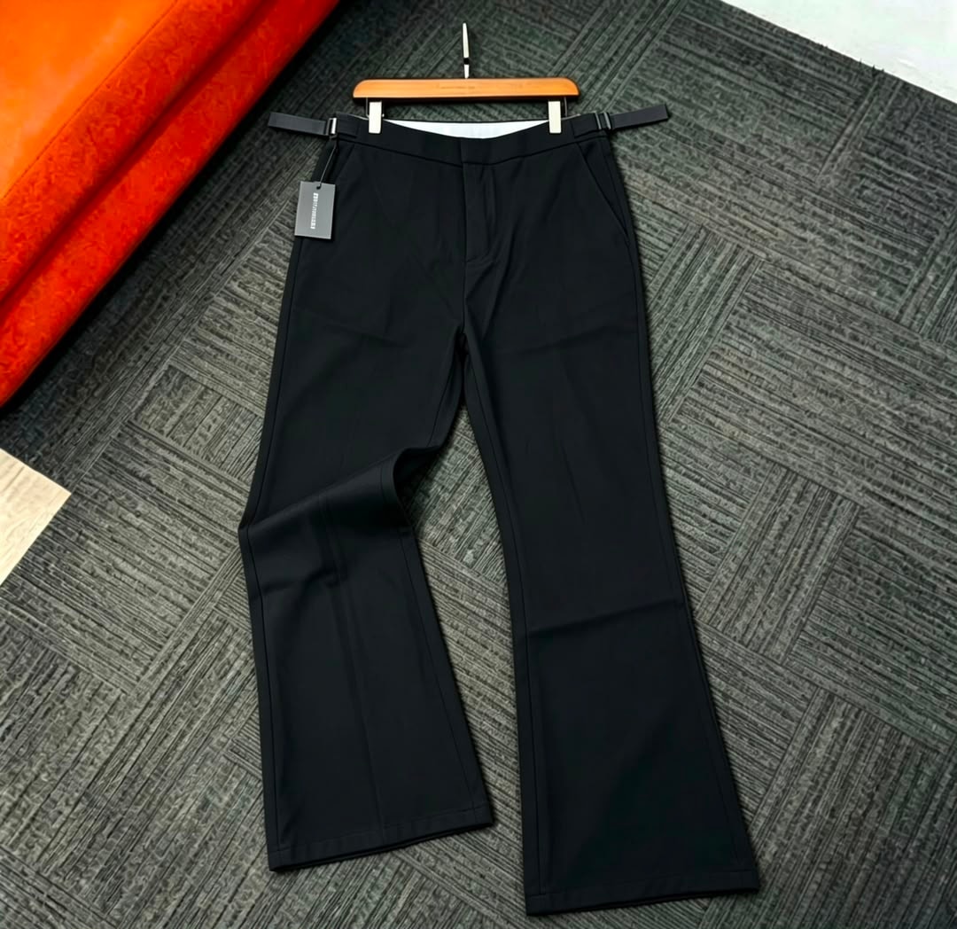Black flare trousers laid flat on patterned rug with tag visible.