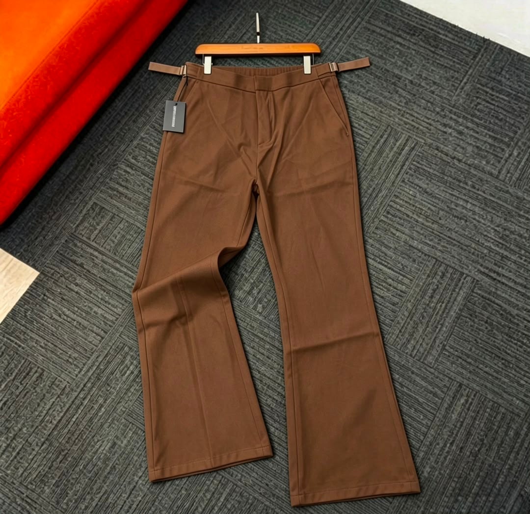 Brown flare trousers displayed on hanger against patterned background.