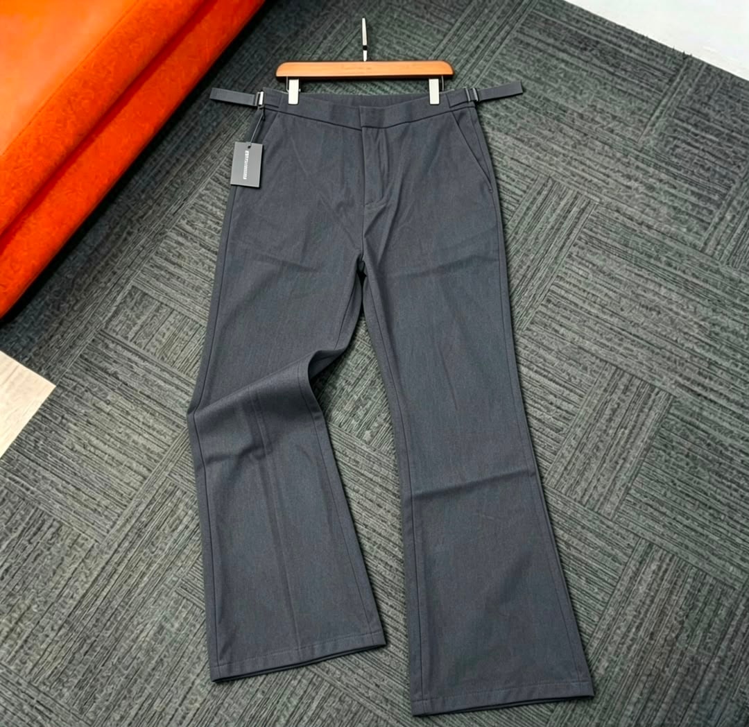 Gray flare trousers laid flat on patterned rug next to orange fabric roll.