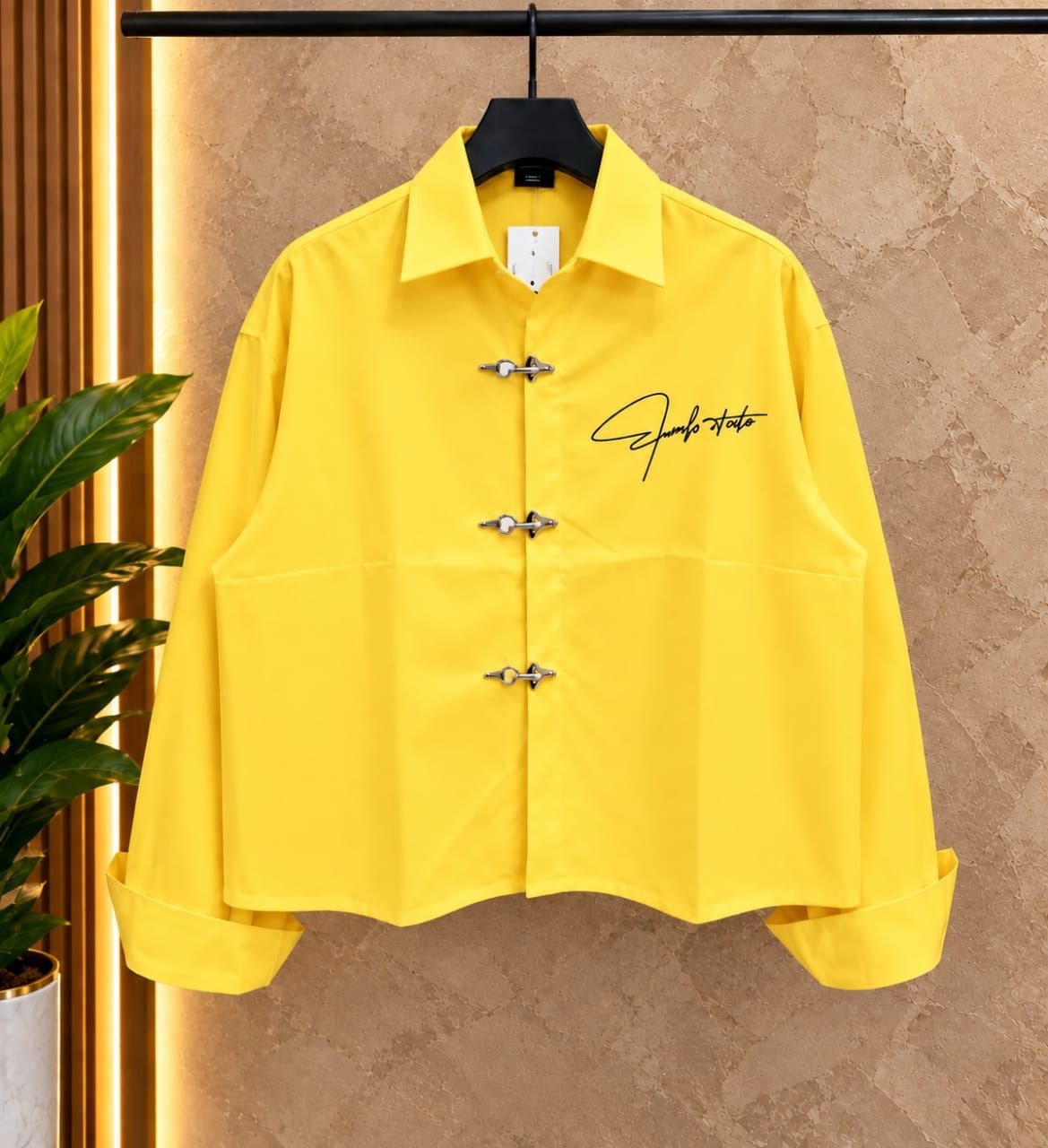 Front view of yellow cropped toggle button shirt on hanger.