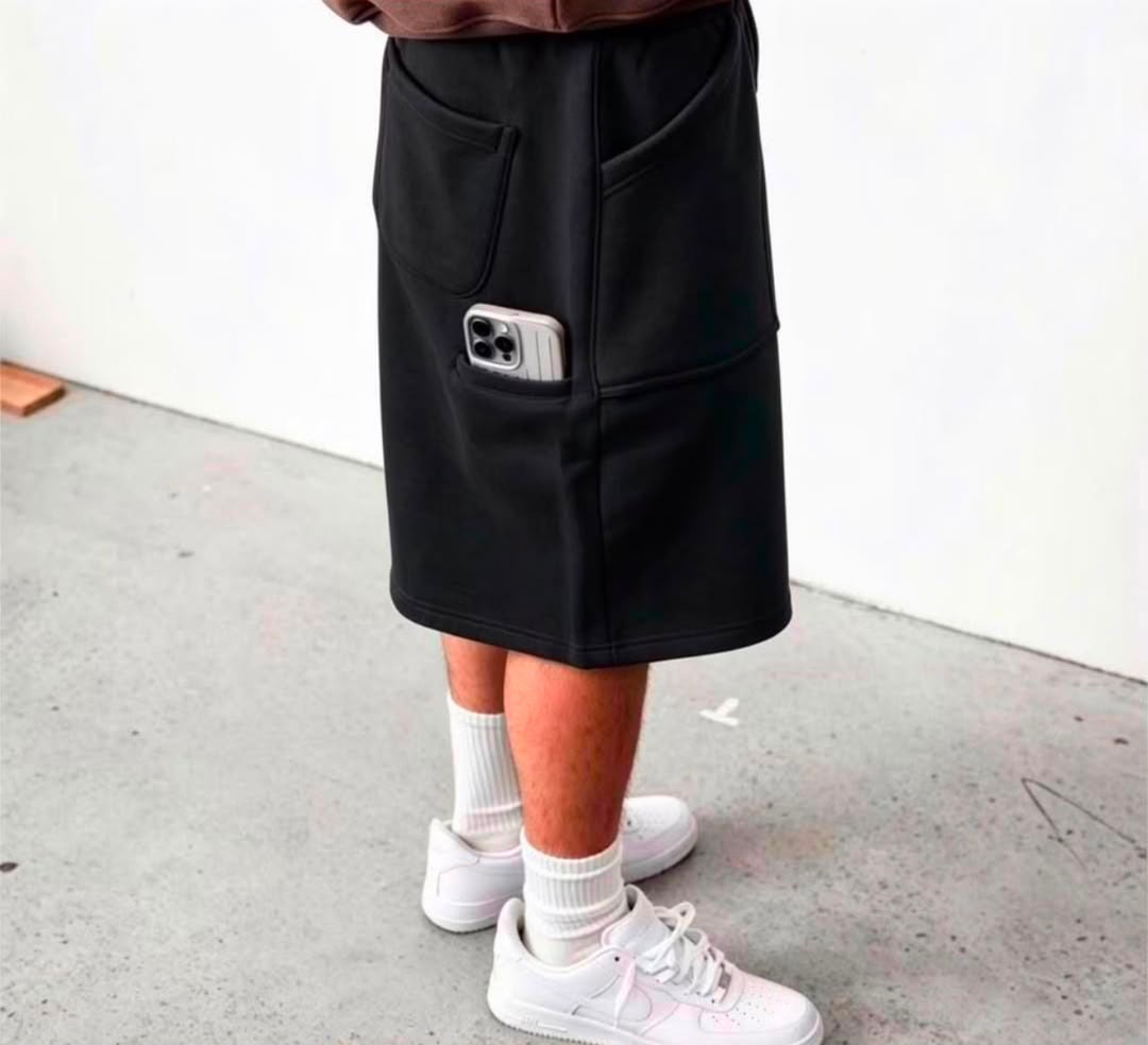 Model wearing black fleece shorts with phone in pocket and white sneakers.
