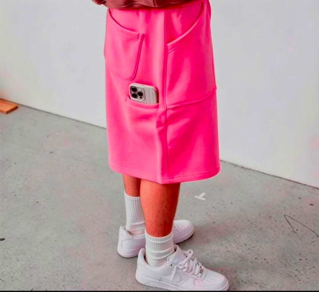 Model in bright pink fleece shorts showing side pockets and phone pocket with white footwear.