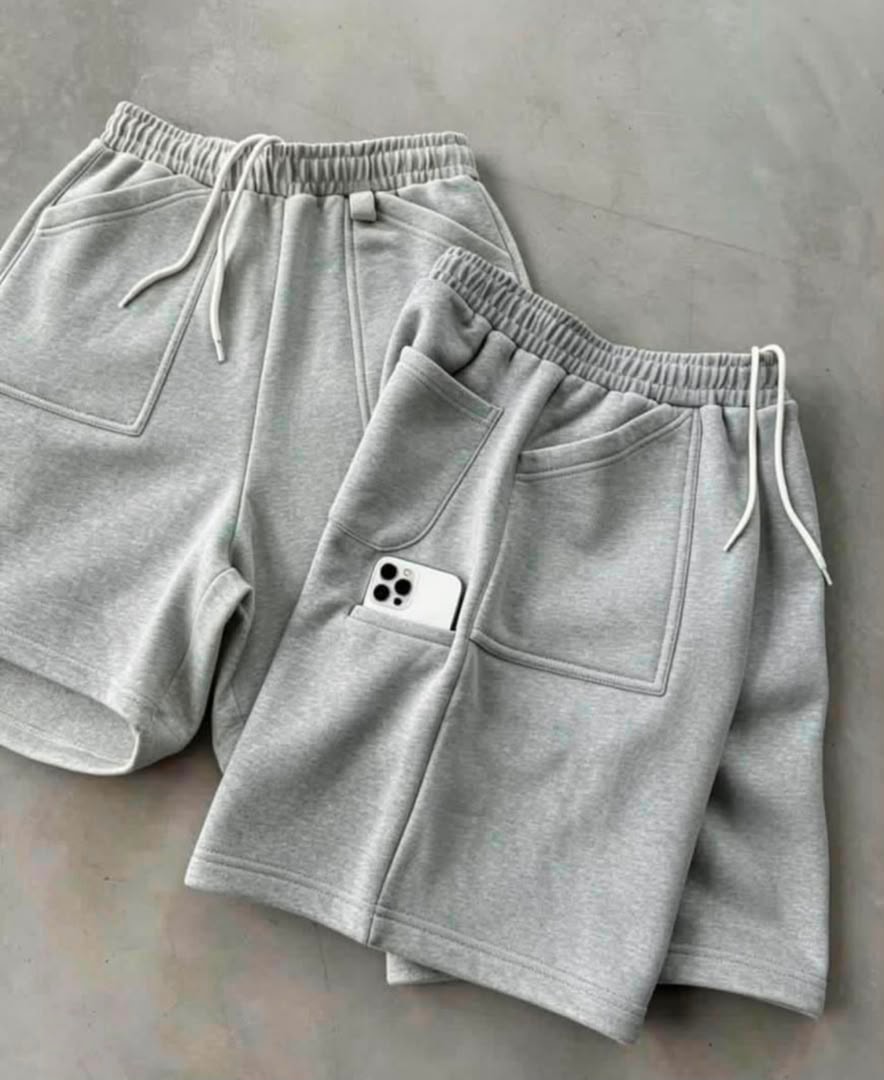 Light gray fleece shorts laid flat with elastic waist, drawstring and phone in pocket.