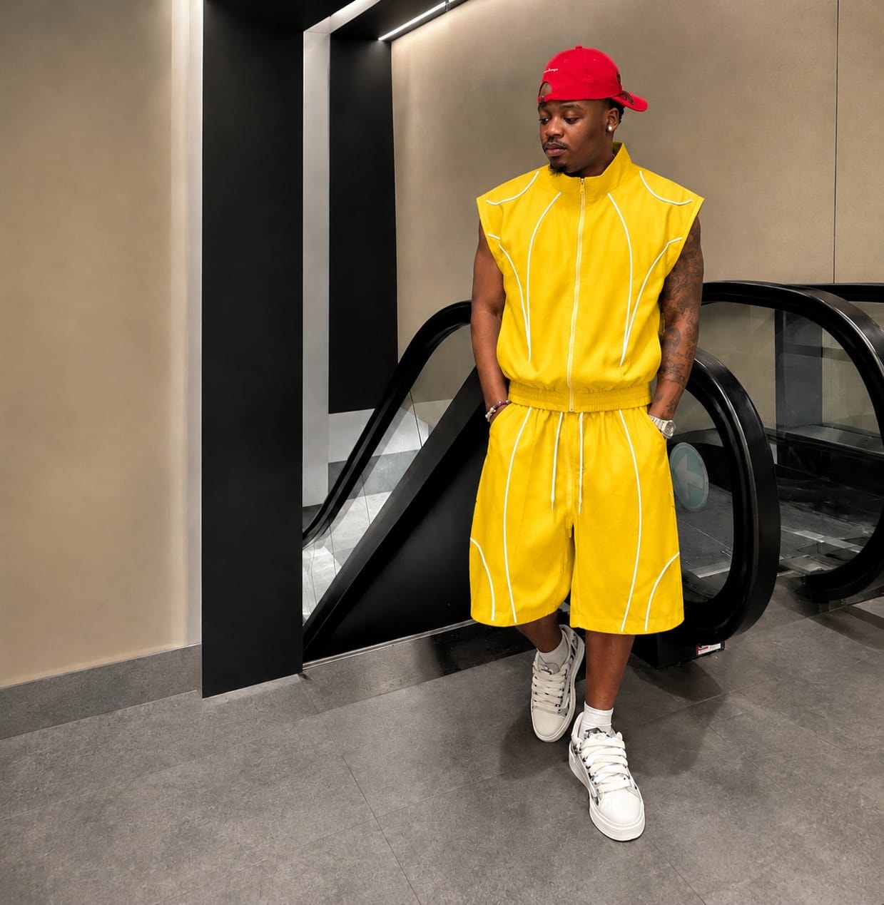 Man modeling yellow sleeveless zip-up vest and shorts with white contrast piping.
