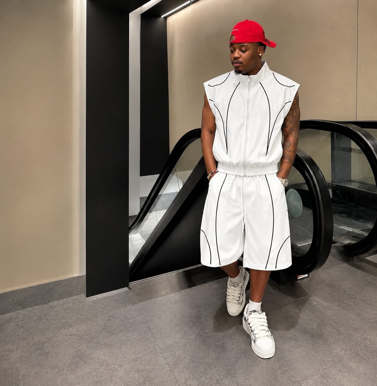 Man modeling white sleeveless zip-up vest and shorts with black contrast piping.