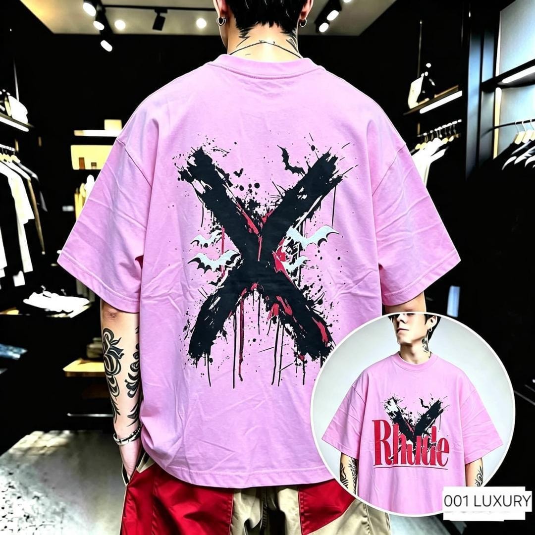 Man modeling pink oversized t-shirt with X bat splatter graphic on the back.