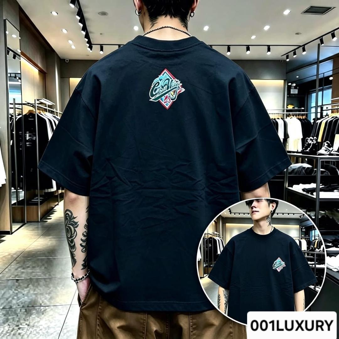 Man in black oversized T-shirt displaying diamond logo on the back.