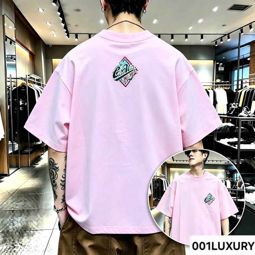 Man in pink oversized T-shirt with colorful diamond logo on back and chest.