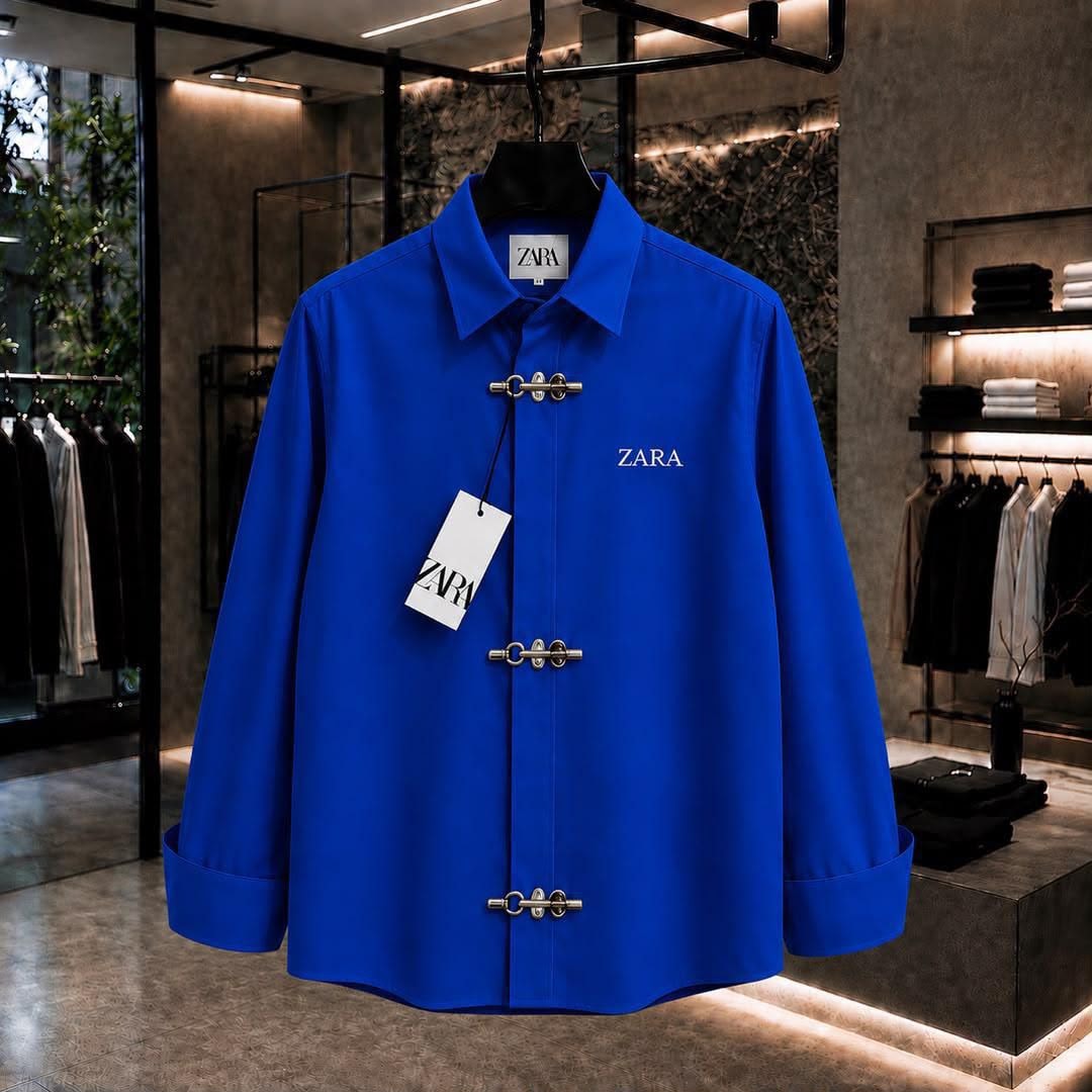 Blue ZARA long sleeve shirt with toggle closures and chest logo in showroom.
