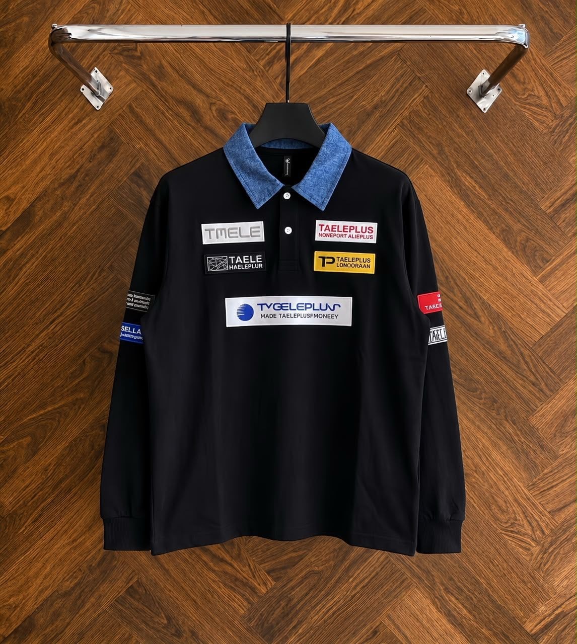 Black long sleeve polo with denim collar and multiple patches on hanger.