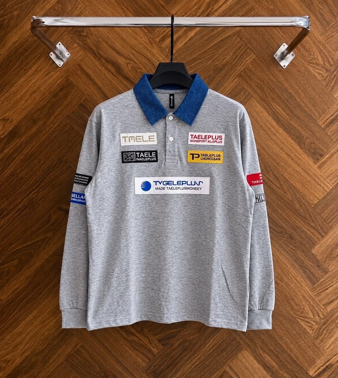 Gray long sleeve polo with denim collar and patches on wooden hanger.