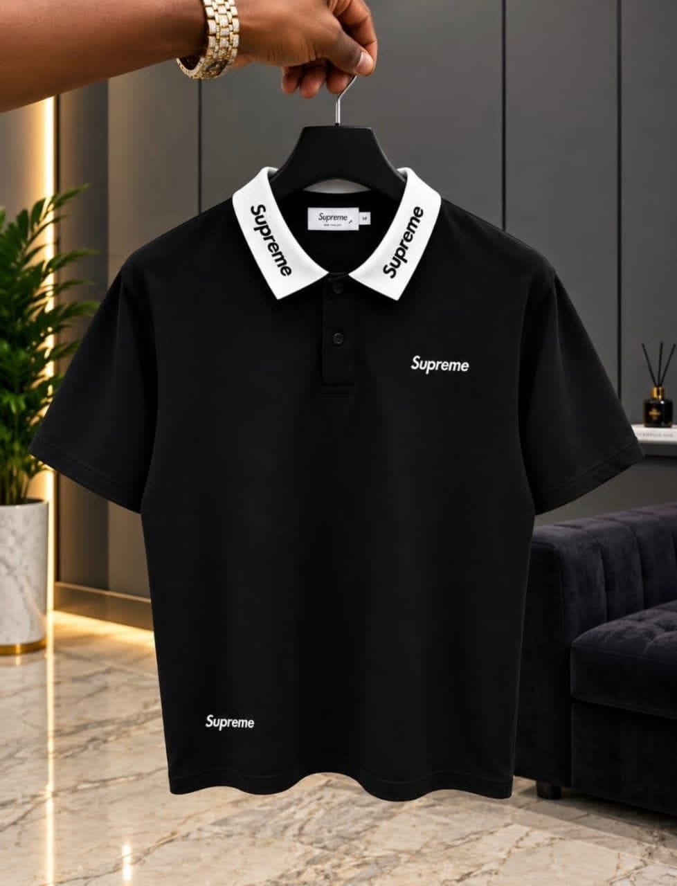 Black Supreme polo shirt with white collar on hanger.