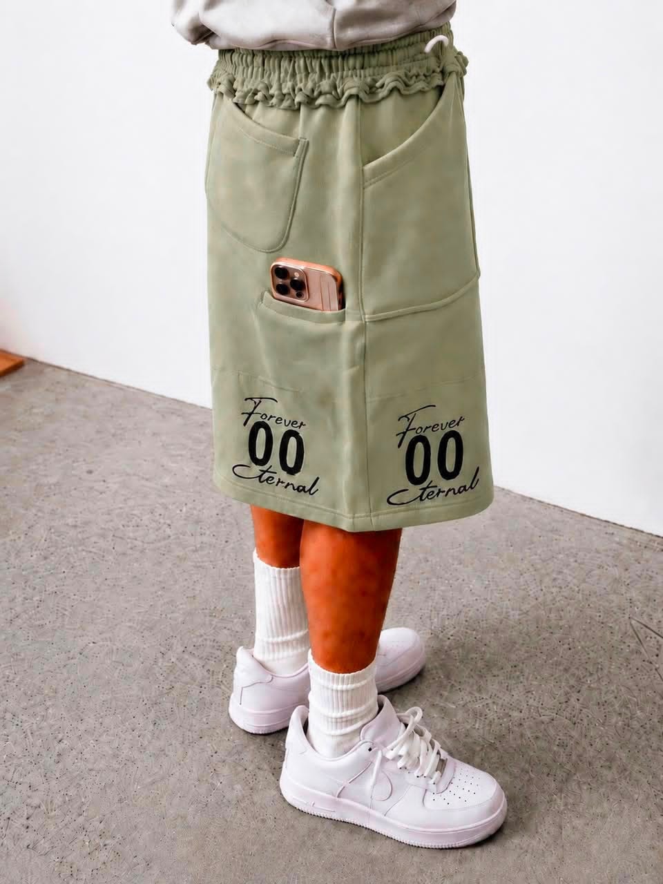 Model wearing olive Forever 00 Eternal cargo shorts with phone in pocket.