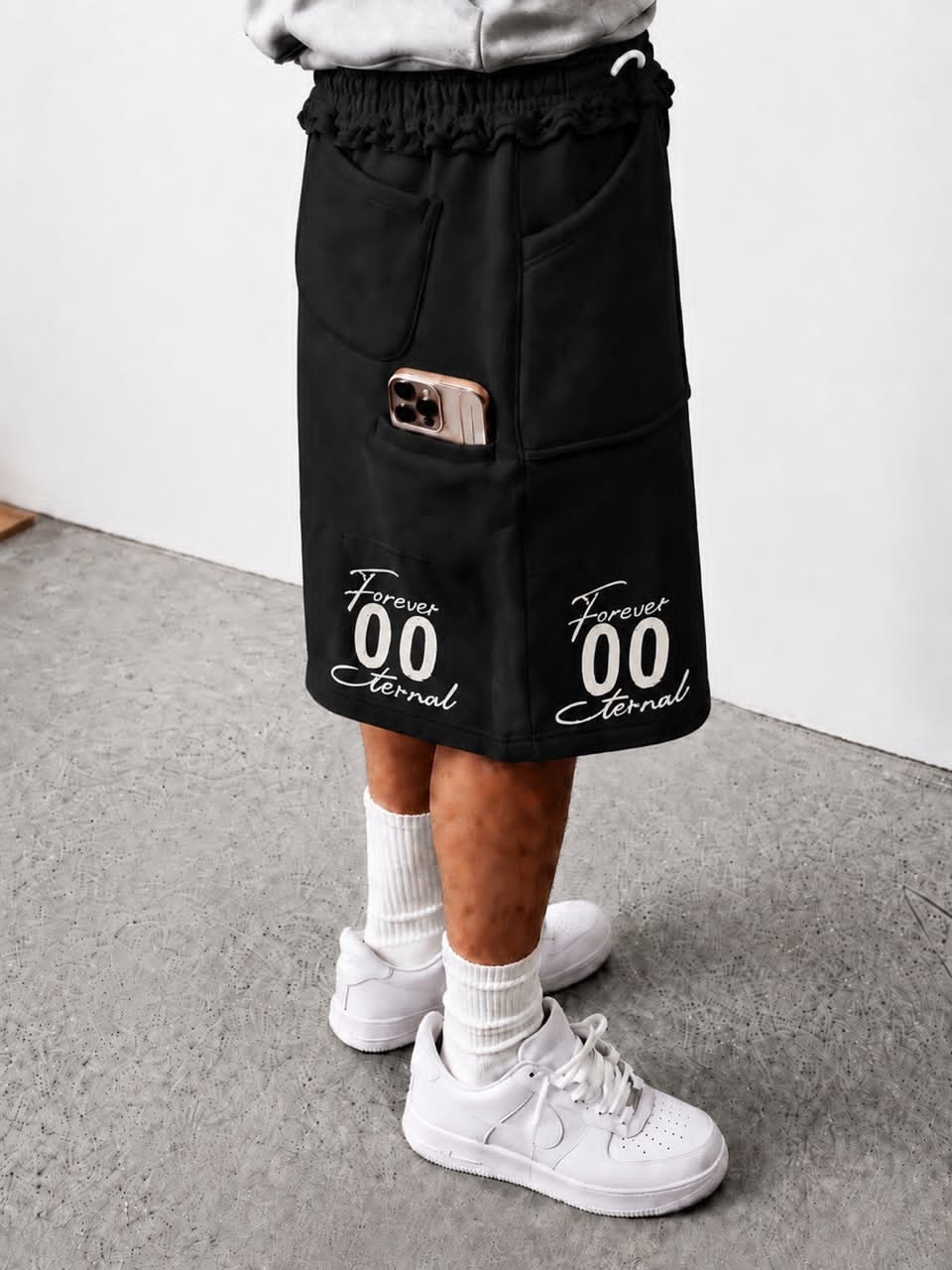 Model wearing black Forever 00 Eternal cargo shorts with phone in pocket.