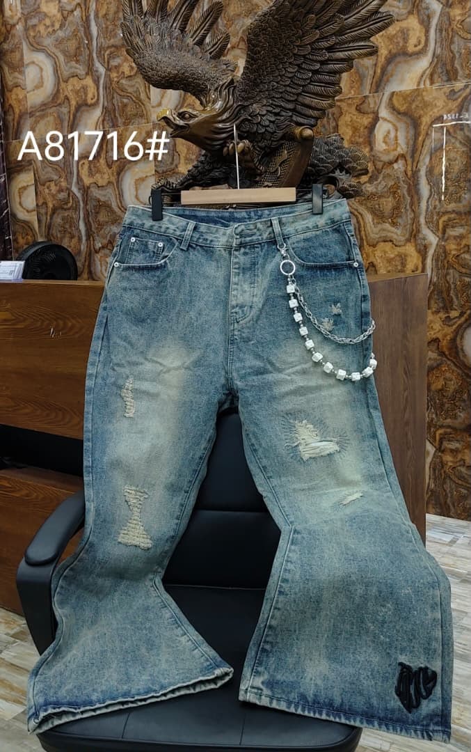 Light blue ripped and distressed flared jeans with chain and patches, on display chair.