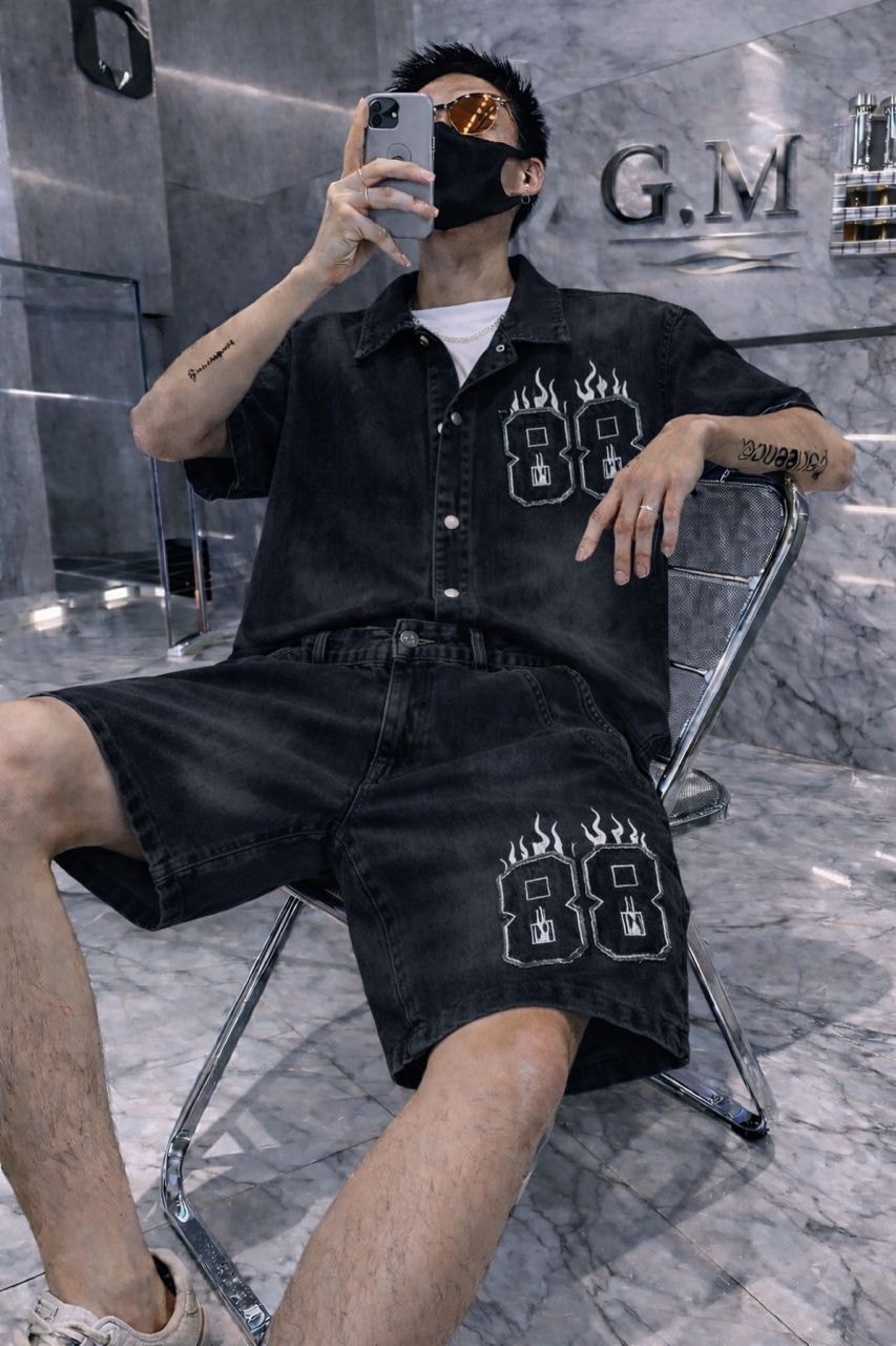 Man wearing black denim shirt and shorts with 88 flame embroidery.
