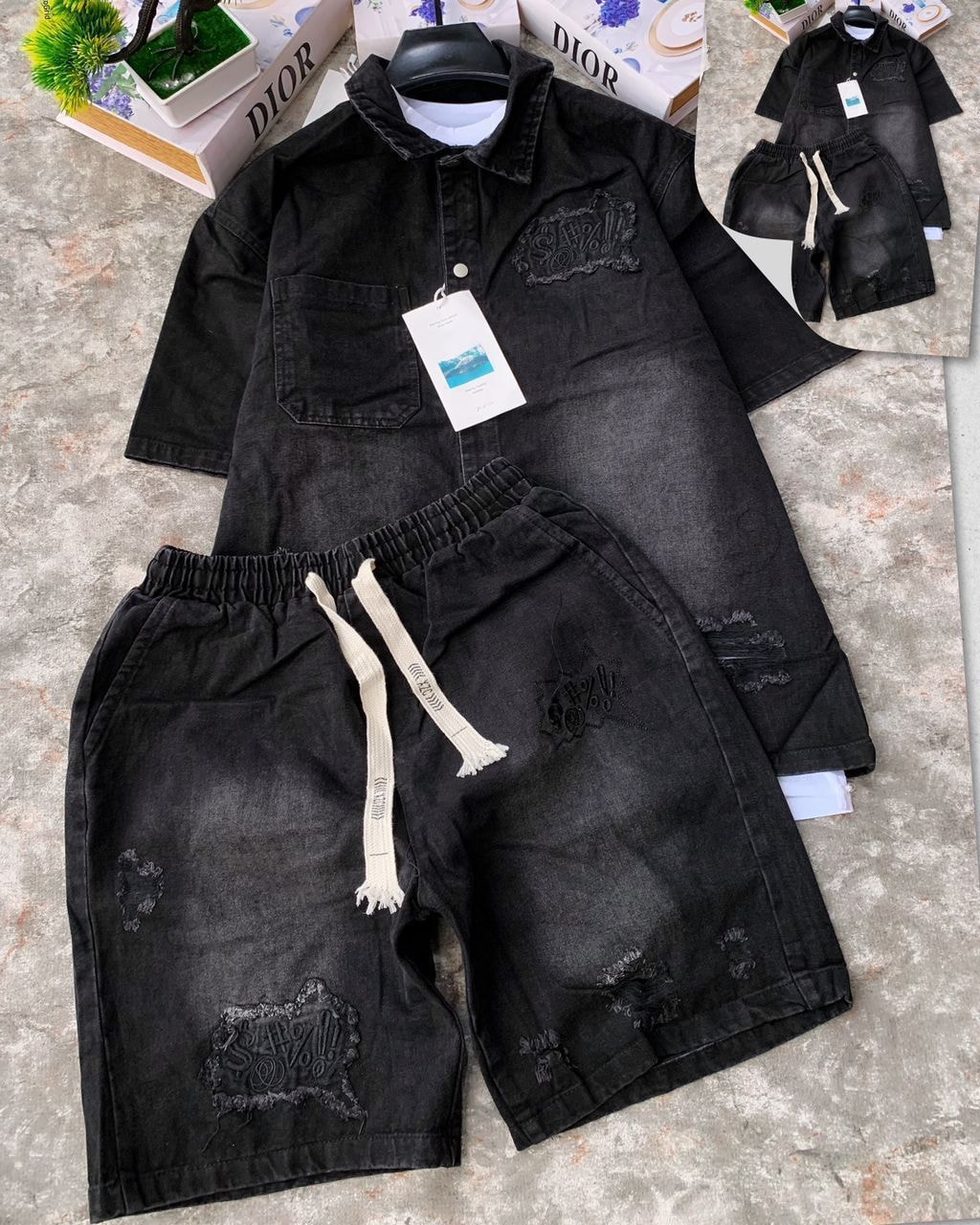 Black denim shirt and shorts two-piece set with embroidery, rips and drawstring laid flat on surface.