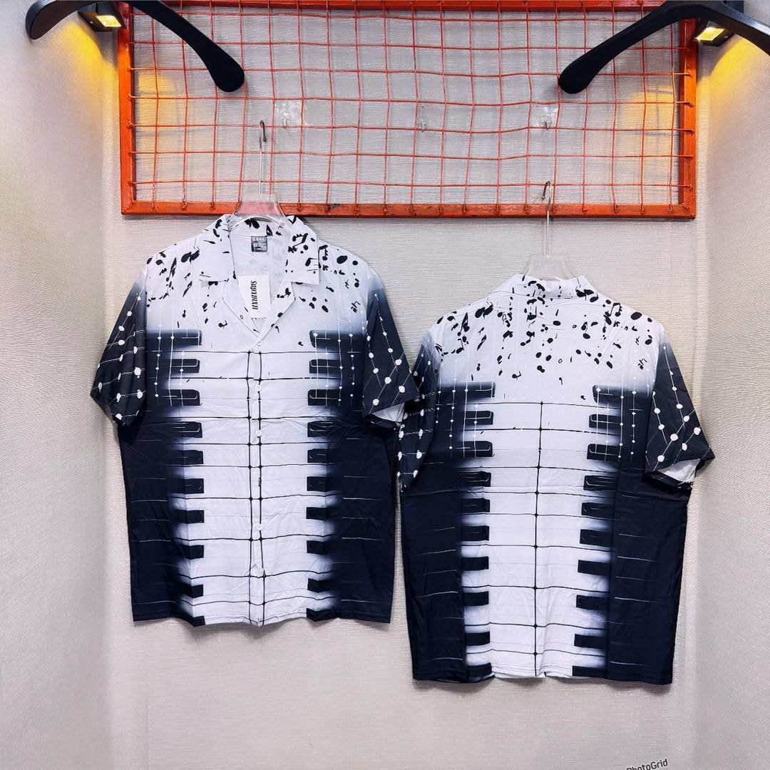 Front and back of short sleeve shirt with piano keys pattern and black gradient splatter.
