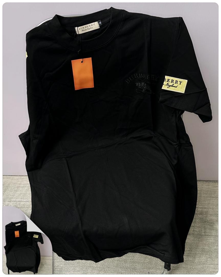 Black Burberry round neck t-shirt laid flat showing chest embroidery, sleeve label and orange tag.