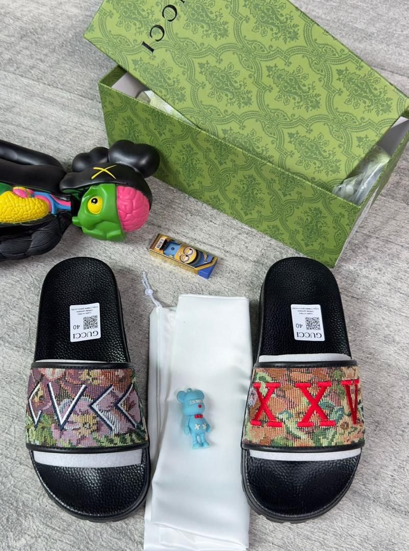 Close-up of Gucci slides with green box, dust bag, and playful accessories.