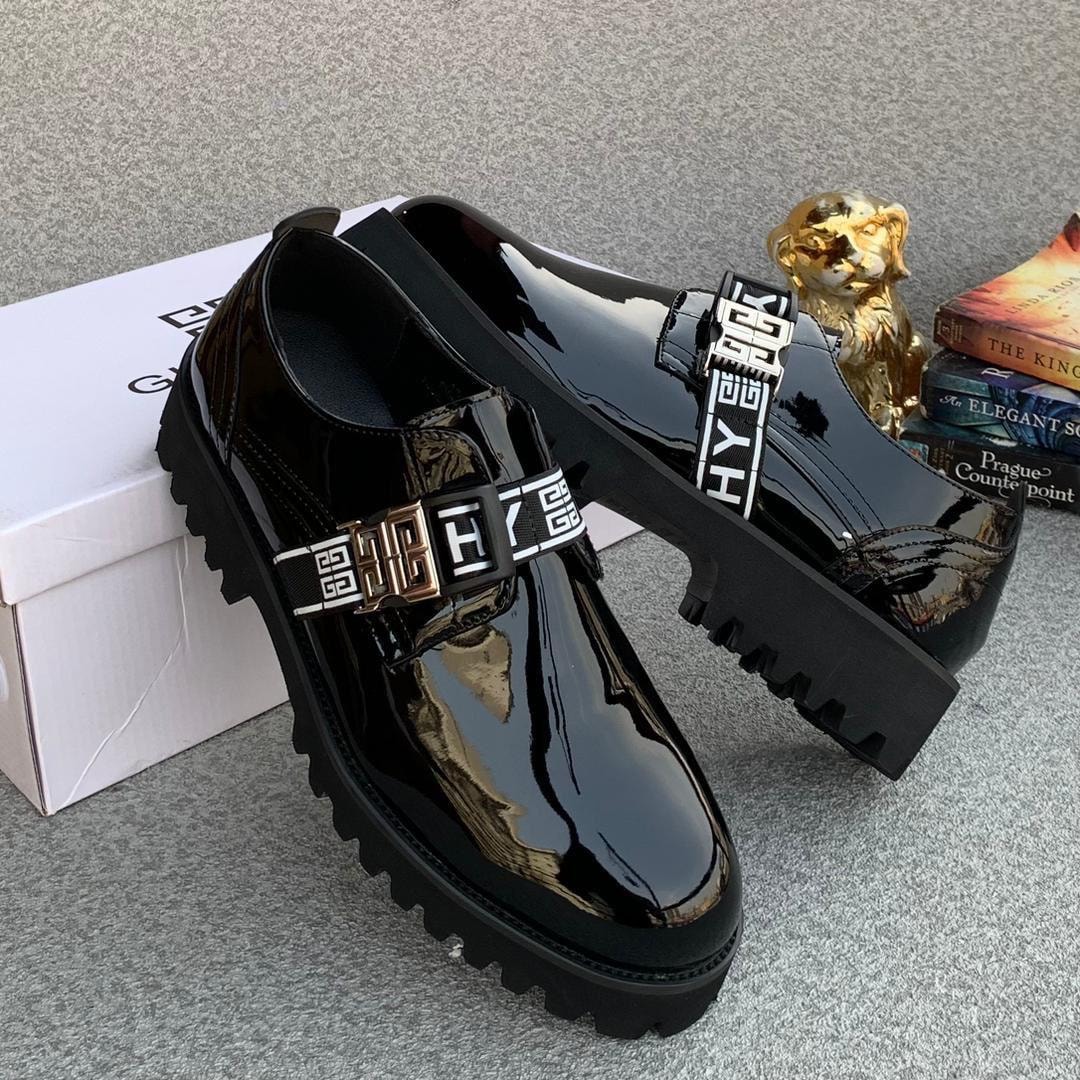 Black patent platform loafers with glossy finish, chunky lug sole, and patterned buckle strap.