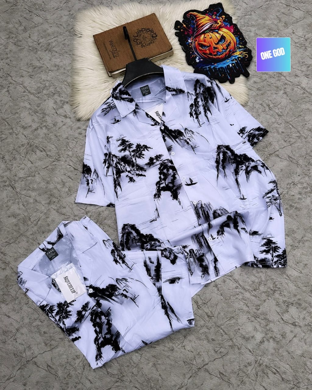 White shirt and shorts with black mountain and tree prints.