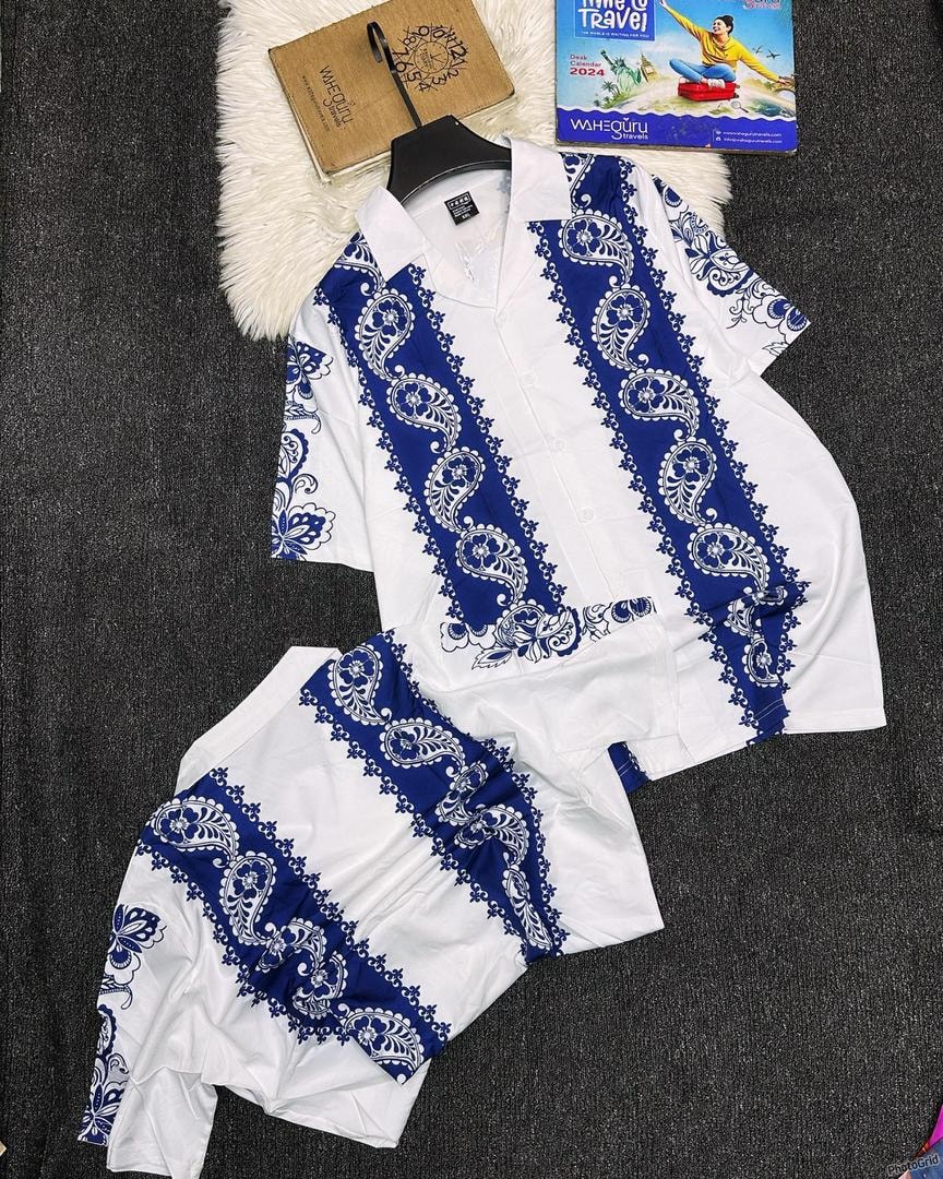 White and blue paisley print shirt and shorts set on dark background with props.