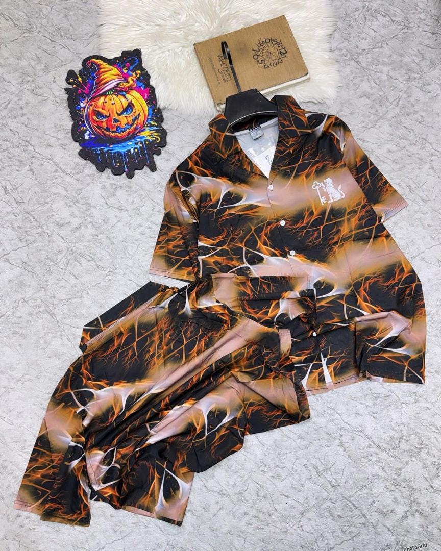 Black and orange flame pattern shirt and shorts set on light surface with pumpkin decoration.