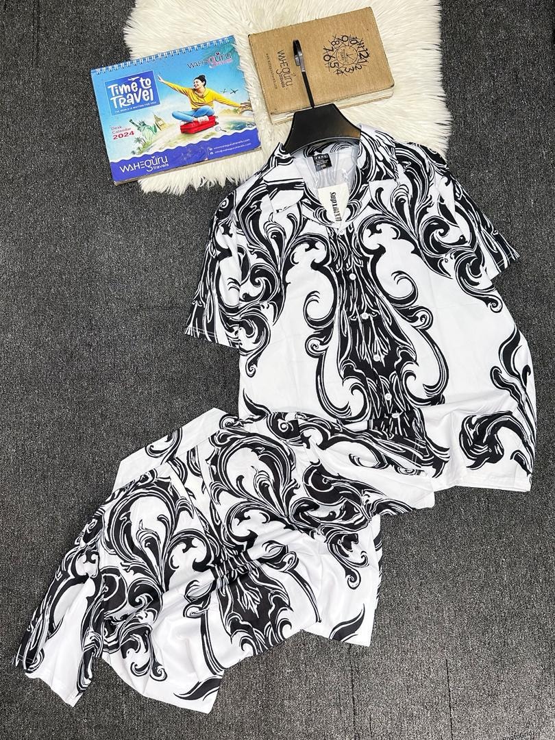 White shirt and shorts with black scroll print laid out with props.