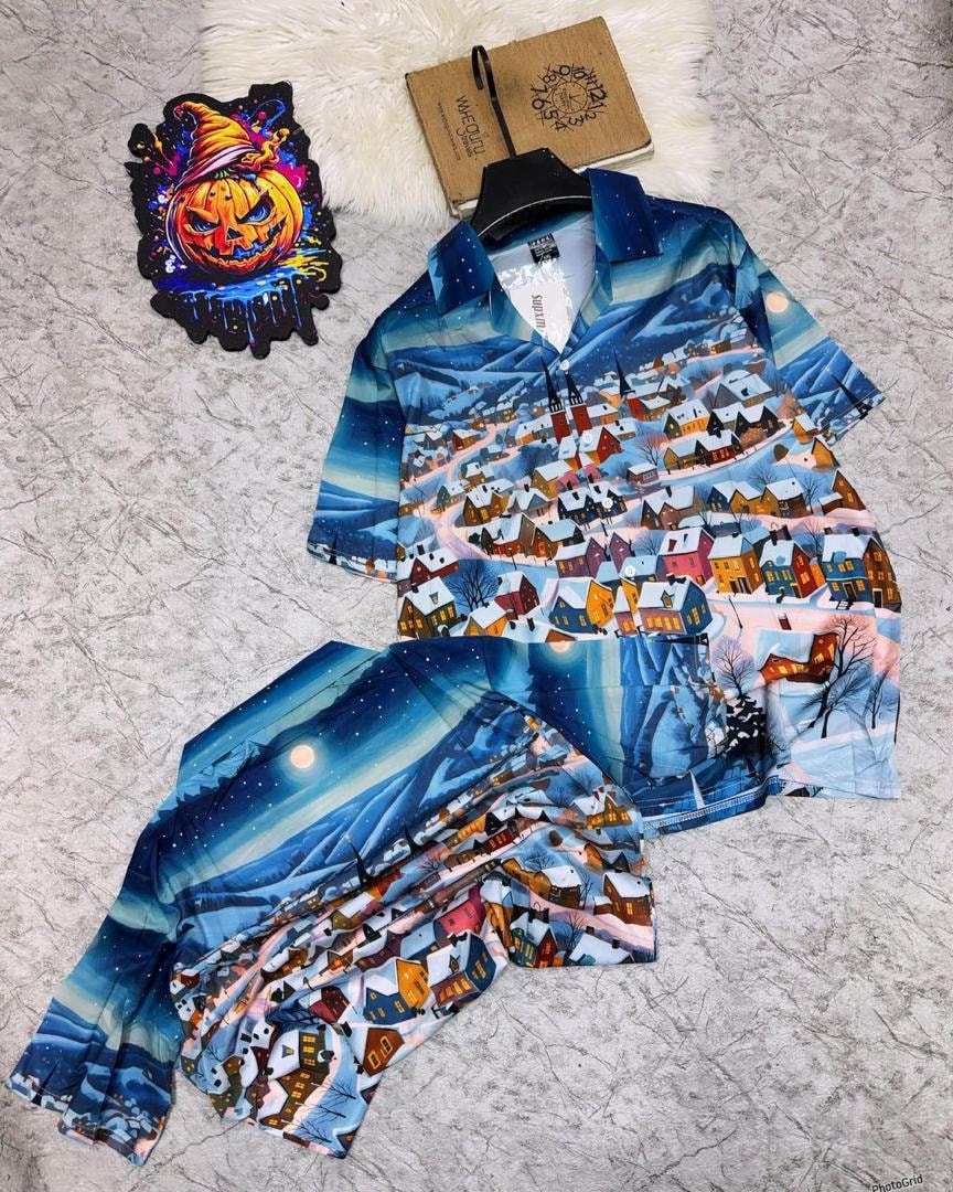 Blue winter village print shirt and shorts set on light marbled surface.
