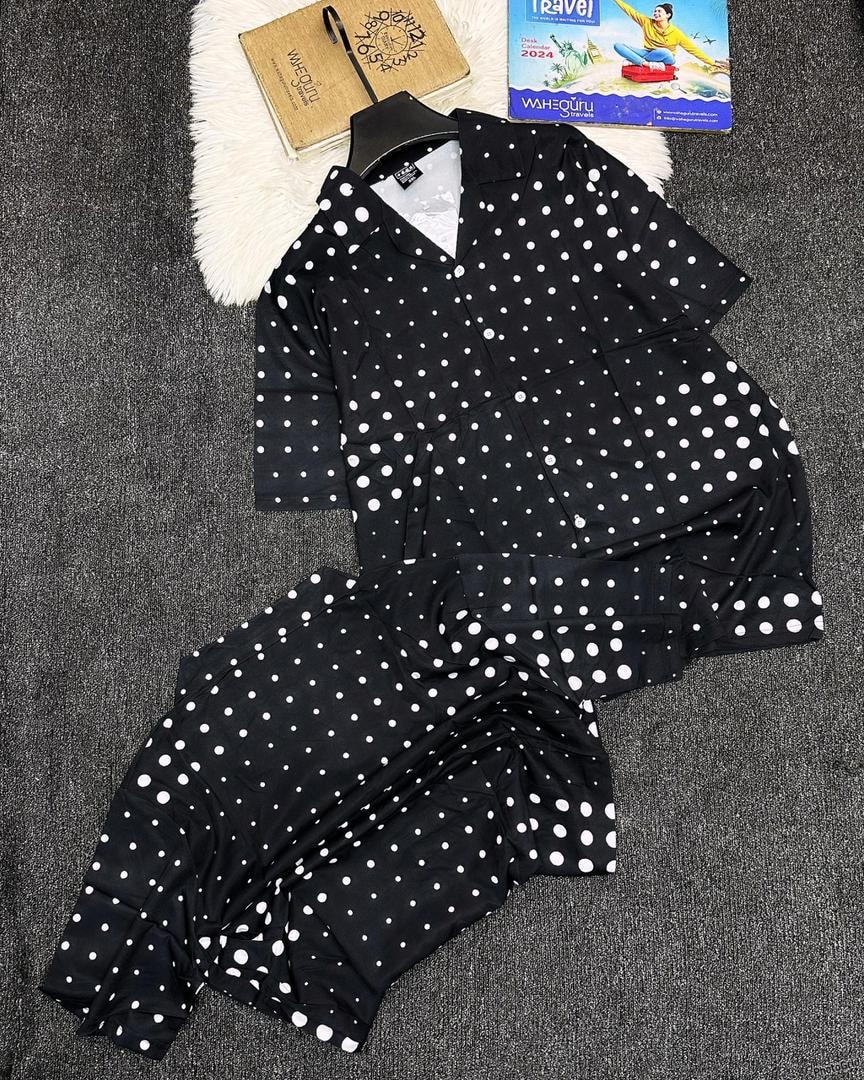 Black polka dot print short sleeve shirt and shorts set laid flat on dark surface.