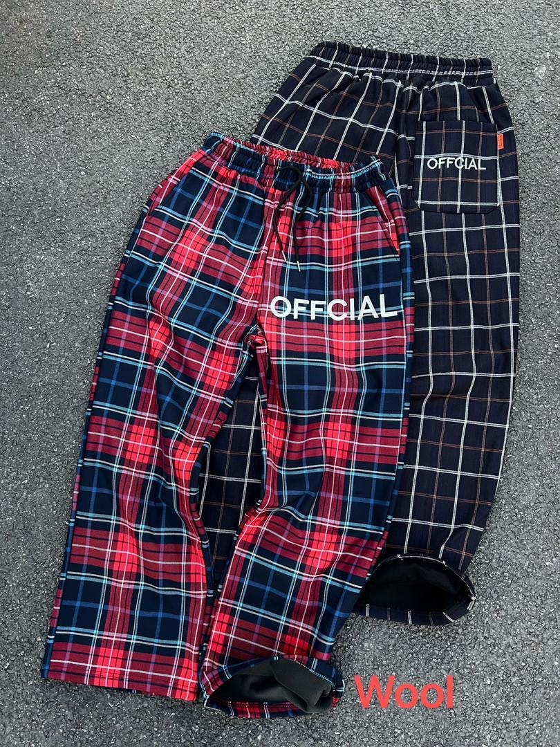 Red and navy plaid Official joggers laid on asphalt with wool lining visible.
