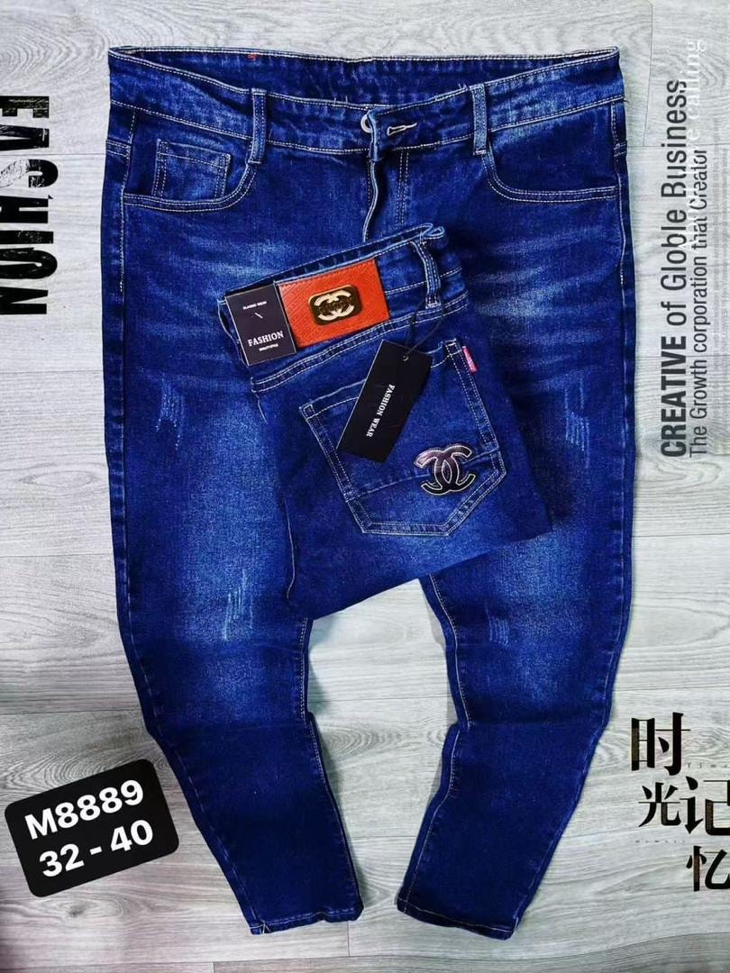 Blue jeans with back pocket logo, patches and tags displayed on wooden surface with size label M8889 32-40.
