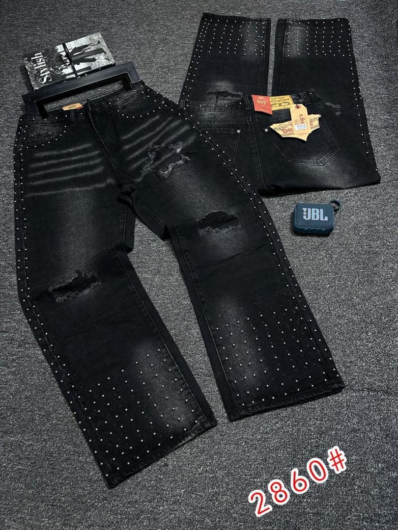 Black ripped baggy jeans with studs, fades, and distressing laid flat with tags.