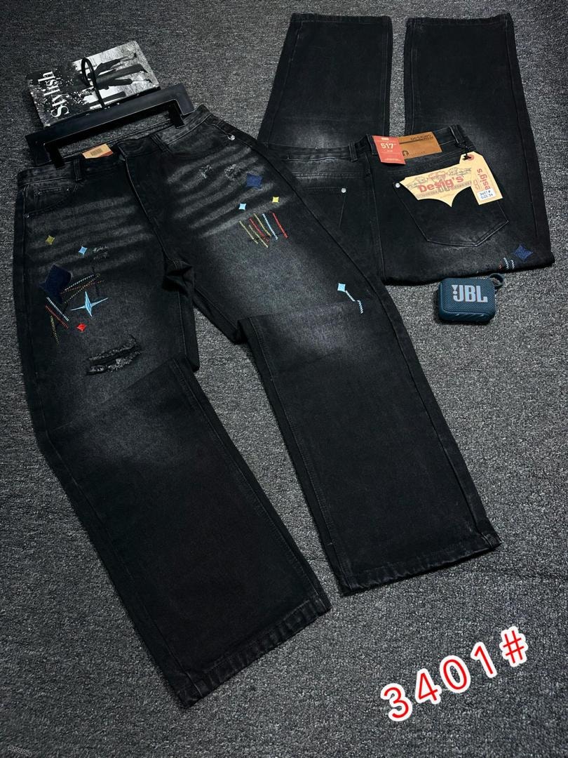 Black baggy jeans with multicolored patches, rips and embroidery details in flat lay.