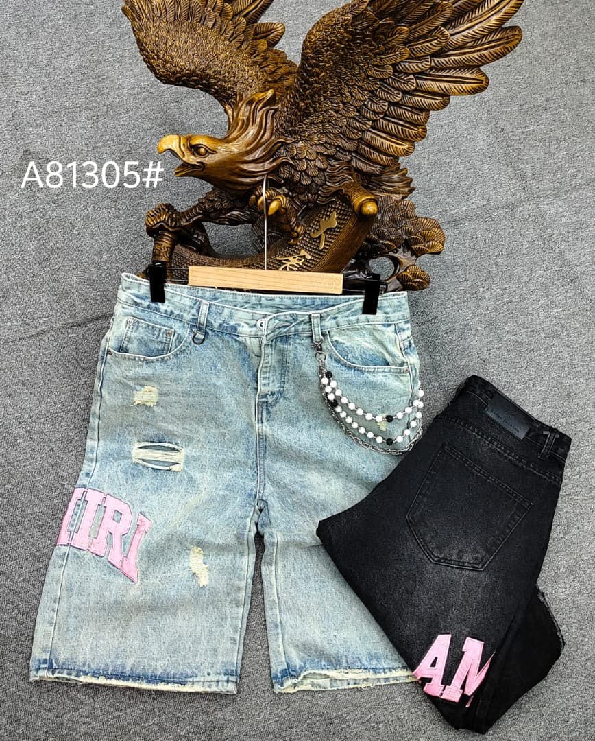 Light blue baggy AMIRI jorts on hanger with chain detail next to folded black pair.