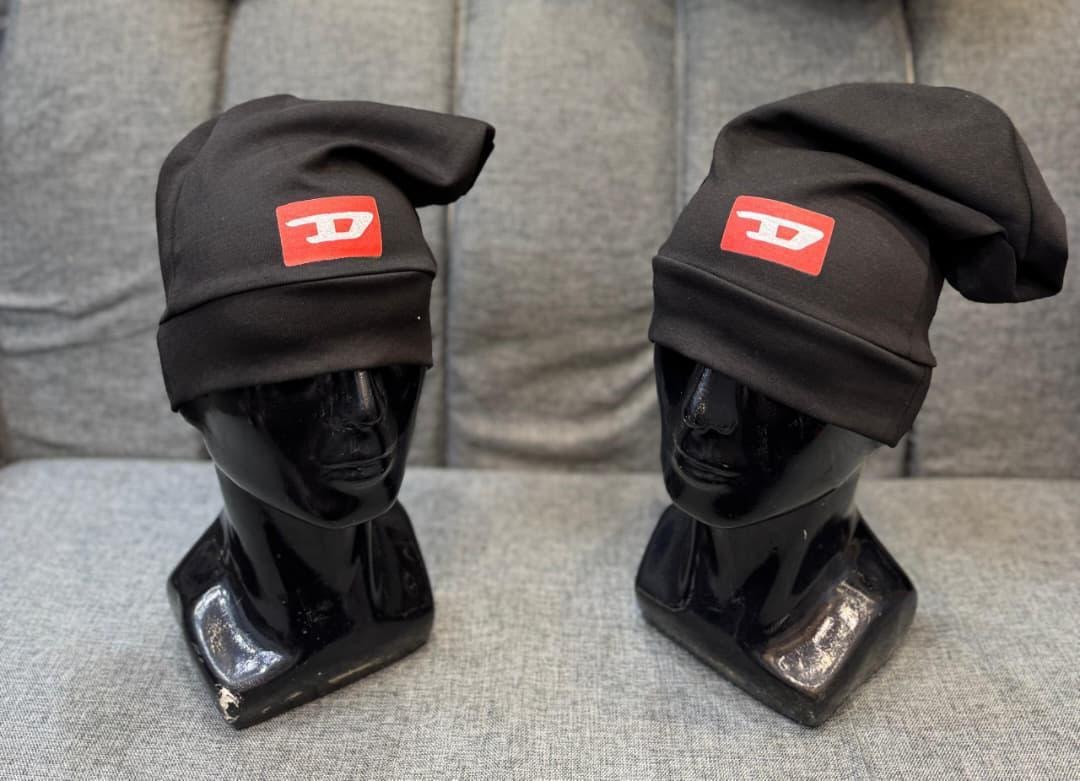 Black Diesel slouch caps with red D logos on black mannequin heads.