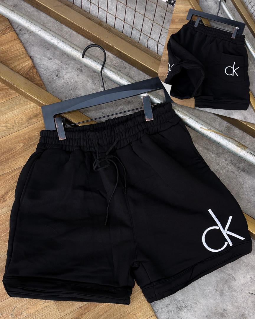 Black unisex fleece shorts with white CK logo on leg and back pocket view.
