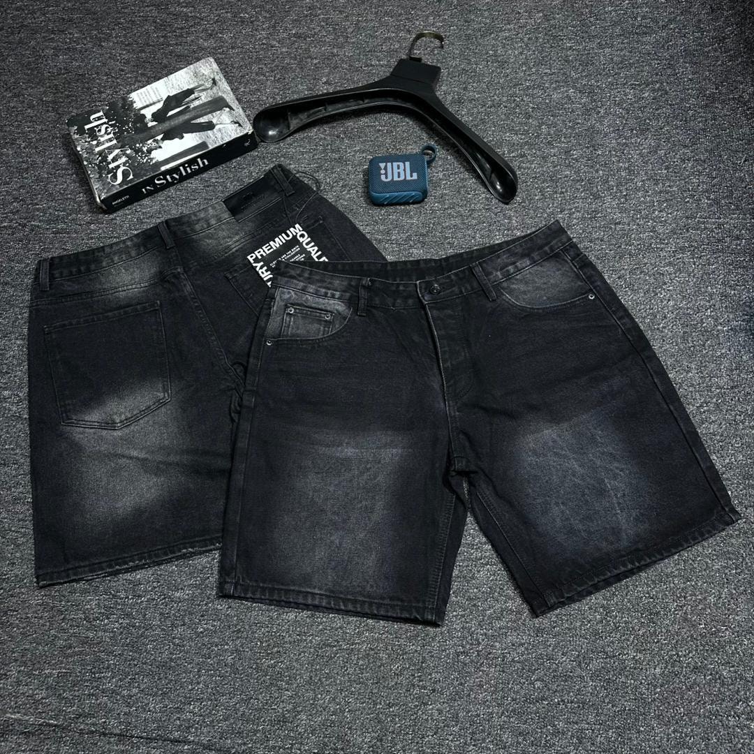 Black baggy denim shorts shown in front and back views on gray surface with styling accessories.