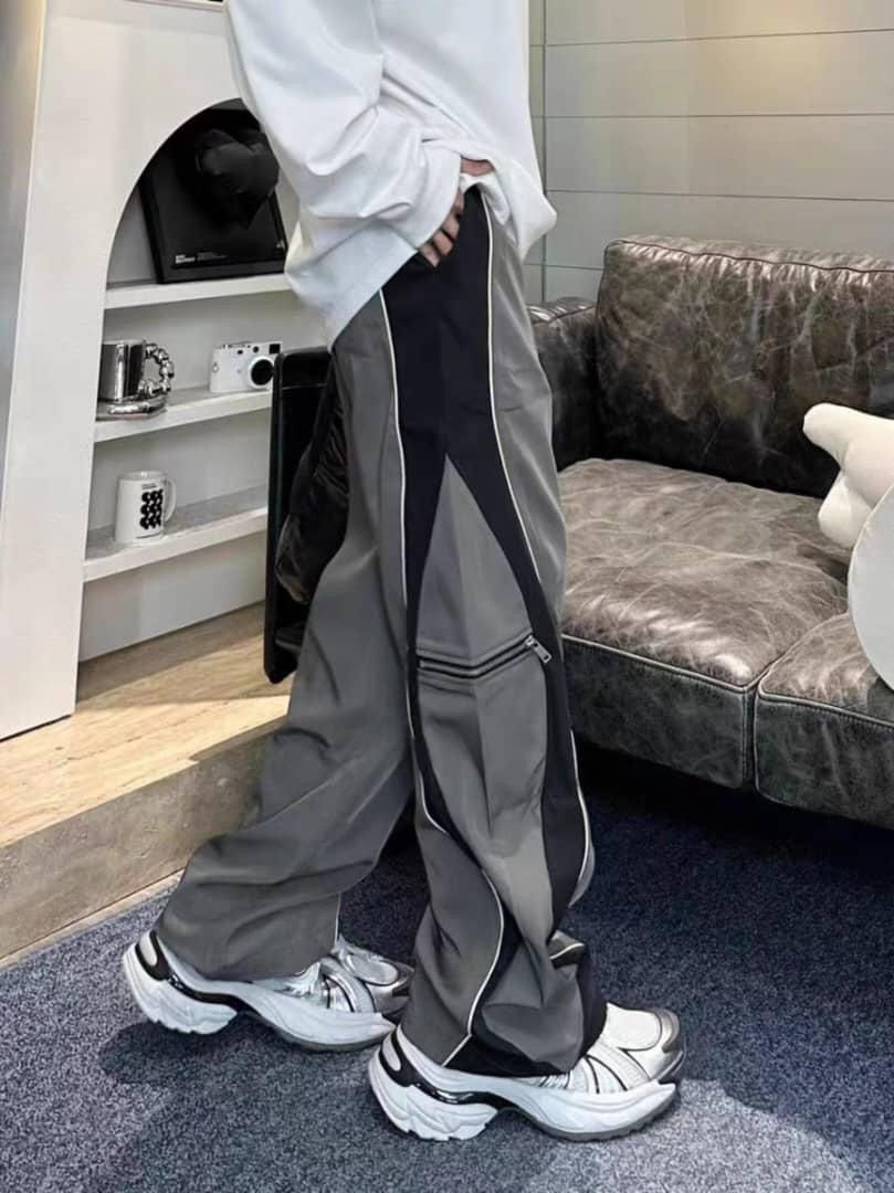 Side view of model in gray panelled joggers showing fit and pocket details.