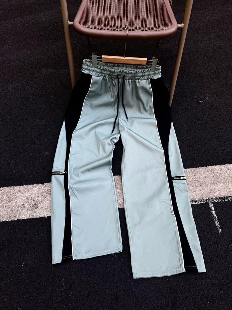 Light blue colorblock joggers with black side panels and zip pockets on hanger.