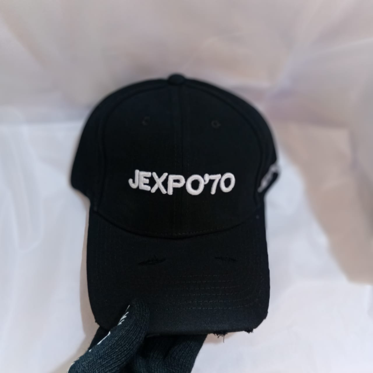Black cap with JEXPO'70 embroidery on front and distressed brim.